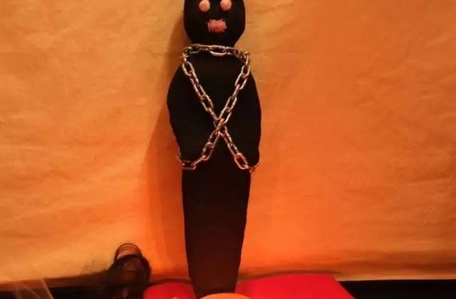 Real Voodoo Love Spell Caster in USA - Chained dark figure on a red cloth altar with small oil lamps
